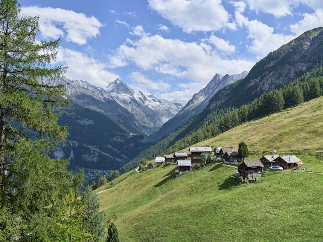 Green valley with a Swiss mountain village and hiking trail in summer